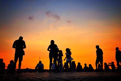 Silhouette people on beach against sky during sunset