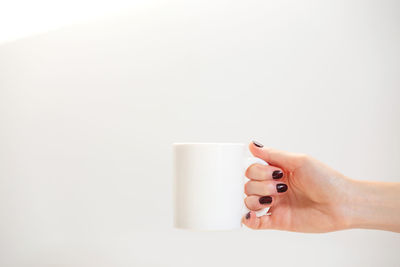 Midsection of woman holding coffee cup over white background