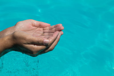 Close-up of hands cupped over swimming pool