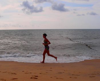 Full length of boy on beach against sky during sunset