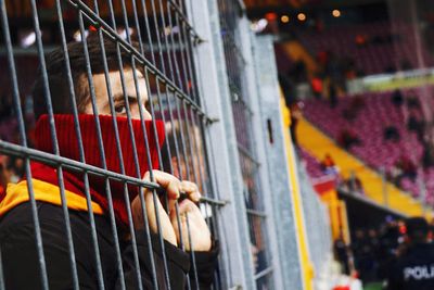 Portrait of man in cage against building