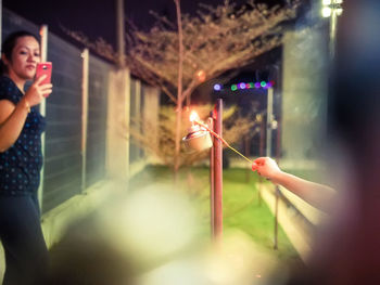 Woman holding illuminated glass at night