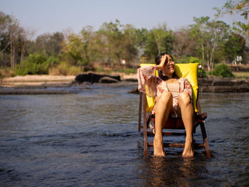 Full length of woman sitting on shore against sky