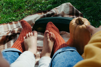 Kid's and woman legs. family sitting outdoors with pumpkins and squashes
