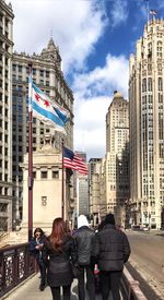 Rear view of people walking in city against sky