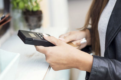 Midsection of female customer paying through credit card at food truck