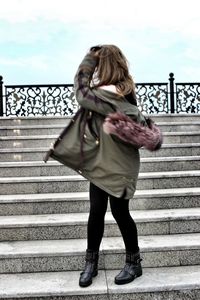 Full length of woman standing by railing against sky