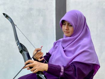 Portrait of woman holding archery set outdoors