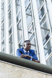Full length portrait of young man sitting in building