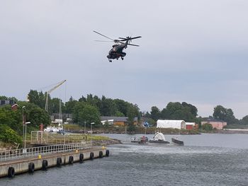 Helicopter flying over river against sky