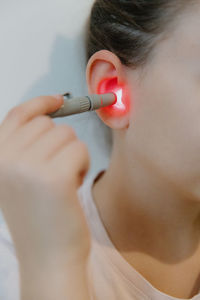 A girl treats her ear with an infrared light device.