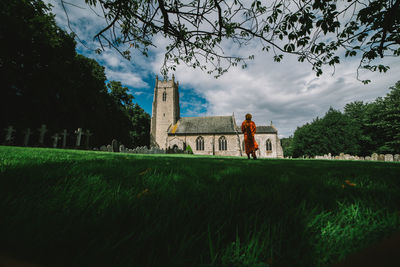 Built structure by trees and buildings against sky