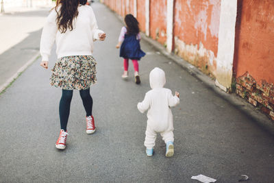 Rear view of mother and children walking on street