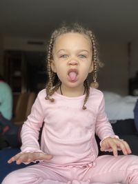 Portrait of cute girl sitting and making faces at home