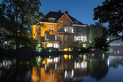 Reflection of trees and buildings on lake at night