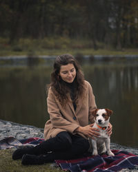 Portrait of woman with dog sitting in lake