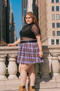 Portrait of young woman standing against built structure