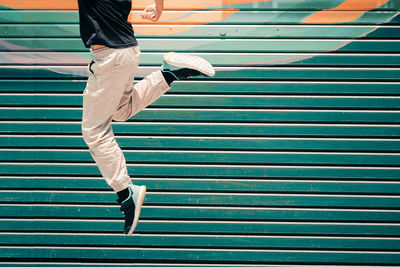 Low section of man jumping against metal wall