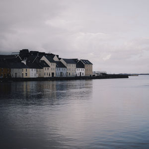 Houses by sea against sky