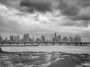 Sea by buildings against sky in city