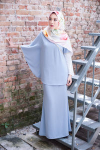 Full length of woman standing against brick wall
