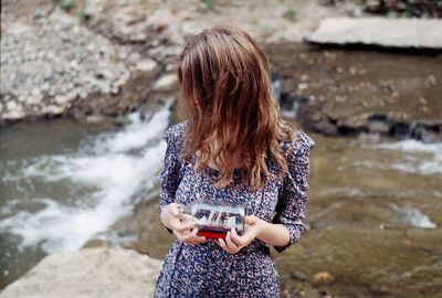 Young woman using phone while standing on shore