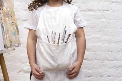 A girl with colored pencils in an apron pocket. little painting artist.