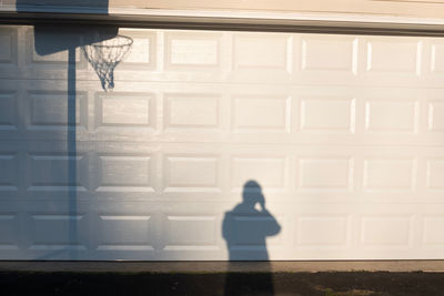 Shadow of person on window against white wall