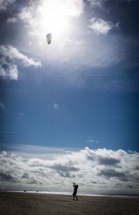 Man paragliding at beach against sky