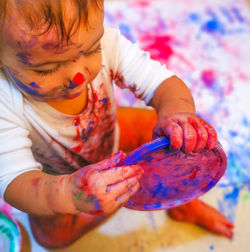 Close-up of baby boy holding lid with watercolor paints