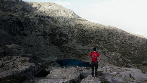 Rear view of man standing on rock against mountain