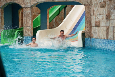 Boy with father enjoying on water slide 