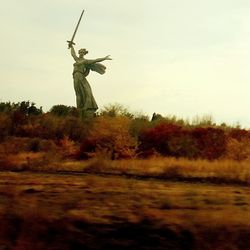 Statue on field against sky