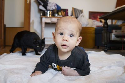 Portrait of cute baby boy by cat at home