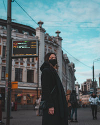 Rear view of woman standing on street in city