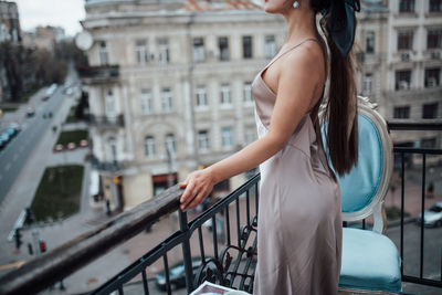 Midsection of woman standing by railing in city