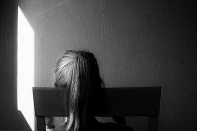 Rear view of woman sitting on chair at home