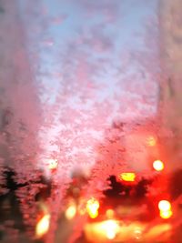 Close-up of wet illuminated lights against sky during sunset