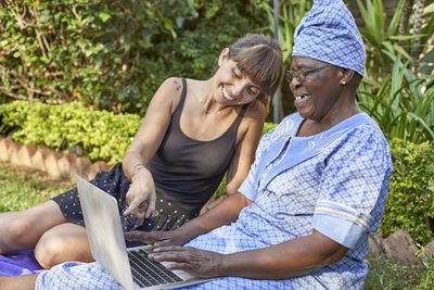 Friends using laptop while sitting on field