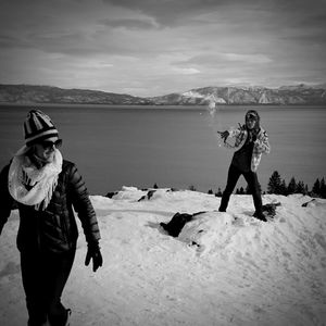 Full length of young couple standing on shore against sky