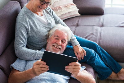 Midsection of man using mobile phone while sitting on sofa