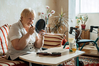 Woman using phone while sitting on table at home