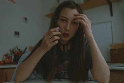 Young beautiful woman smoking cigarette at home