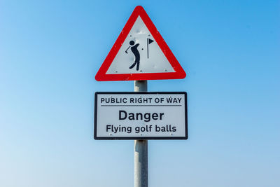 Low angle view of sign board against blue sky