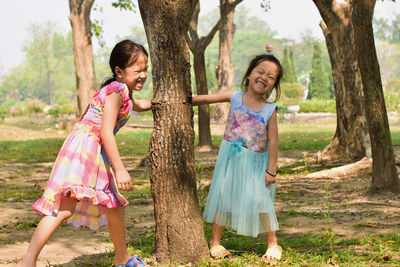 Full length of smiling girl on tree trunk