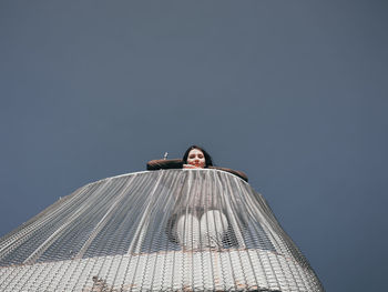 Low angle portrait of woman standing against clear sky