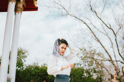 Low angle view of woman standing against trees