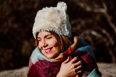 Close-up of smiling woman wearing fur hat and blanket outdoors