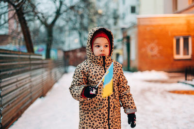 Portrait of girl in warm clothing holding flag outdoors