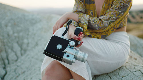 8mm vintage camera held by a girl sitting on the rock in the nature